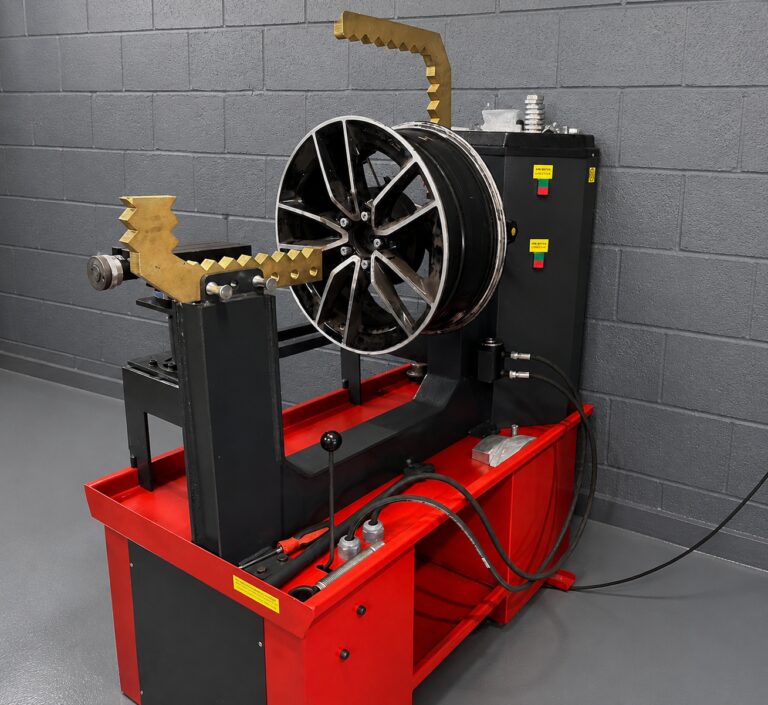 Alloy wheel mounted on a red and black wheel straightening machine at LTC