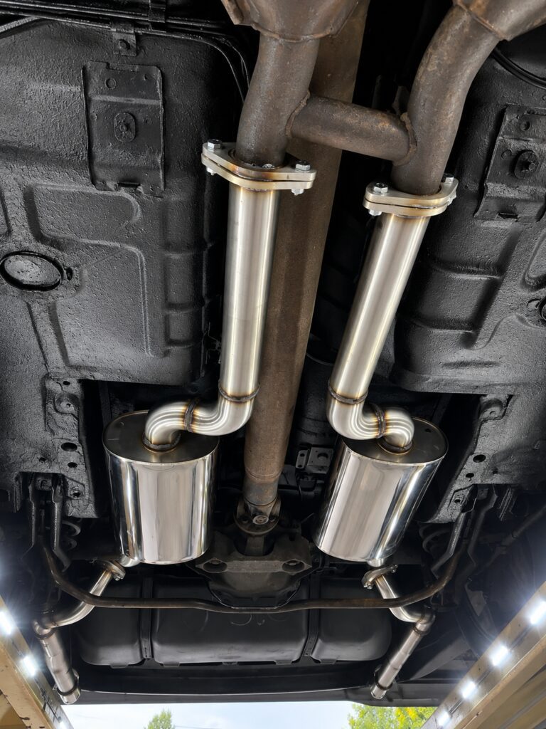 Twin stainless steel exhaust pipes and silencers fitted beneath a vehicle